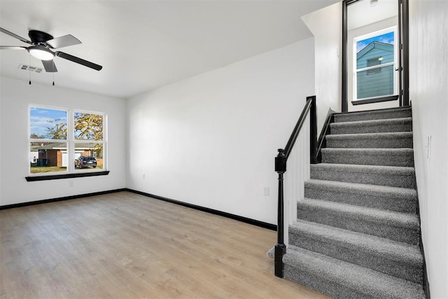 stairs featuring ceiling fan and wood-type flooring