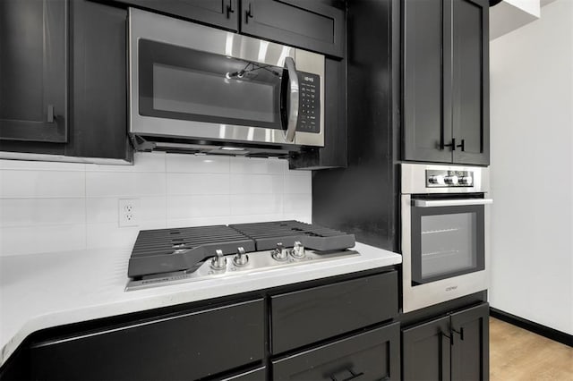 kitchen featuring light wood-type flooring, appliances with stainless steel finishes, and backsplash