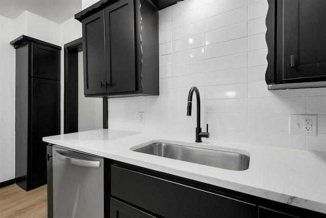 kitchen featuring light wood-type flooring, decorative backsplash, stainless steel dishwasher, and sink