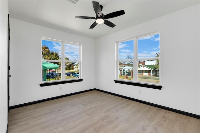 spare room featuring ceiling fan, a healthy amount of sunlight, and light wood-type flooring