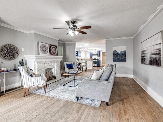 living room featuring a brick fireplace, a textured ceiling, ornamental molding, hardwood / wood-style flooring, and ceiling fan with notable chandelier