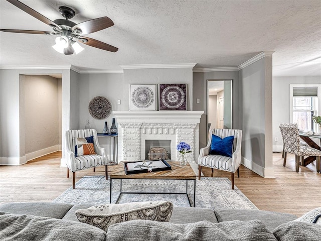 living room with crown molding, a textured ceiling, light wood-type flooring, and a fireplace