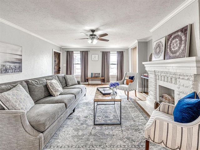 living room featuring crown molding, hardwood / wood-style flooring, ceiling fan, a textured ceiling, and a brick fireplace