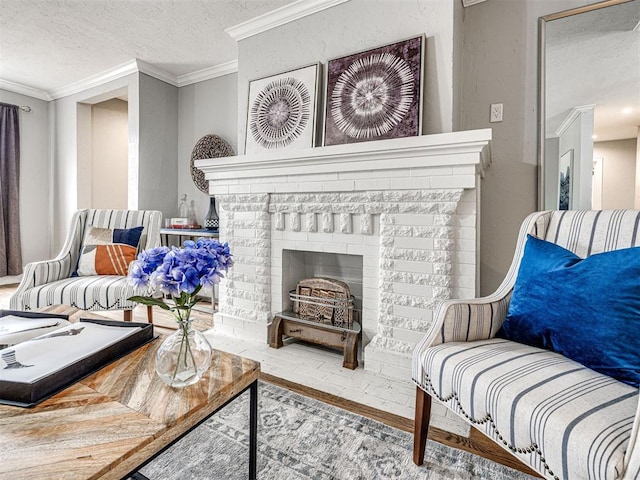 living area with ornamental molding, a brick fireplace, hardwood / wood-style floors, and a textured ceiling