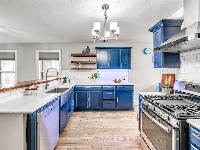 kitchen featuring backsplash, stainless steel appliances, wall chimney exhaust hood, and blue cabinetry