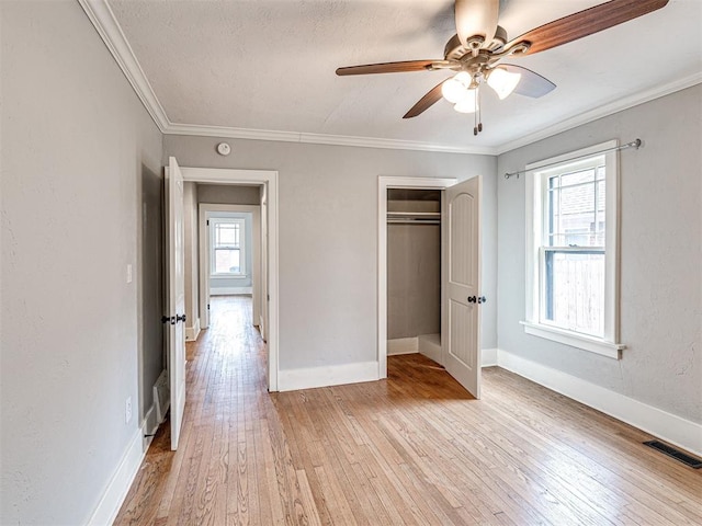 unfurnished bedroom with multiple windows, crown molding, a closet, and ceiling fan