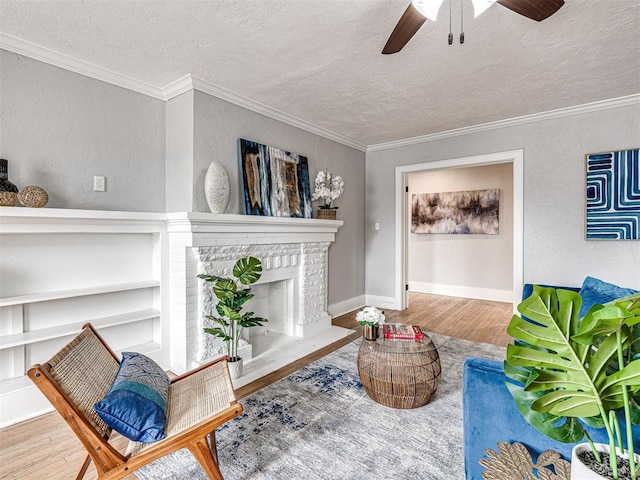 living area featuring a brick fireplace, wood-type flooring, ornamental molding, and a textured ceiling