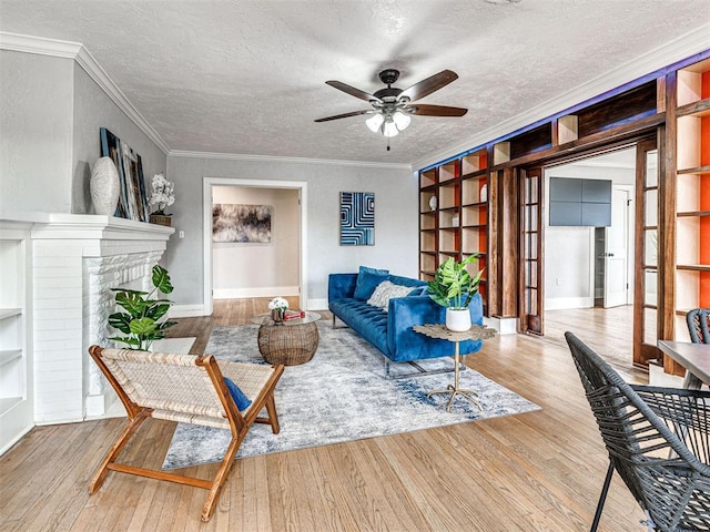 living room featuring crown molding, light hardwood / wood-style flooring, built in features, and a textured ceiling