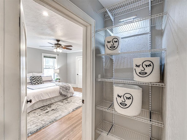 interior space with hardwood / wood-style flooring, ceiling fan, crown molding, and a textured ceiling