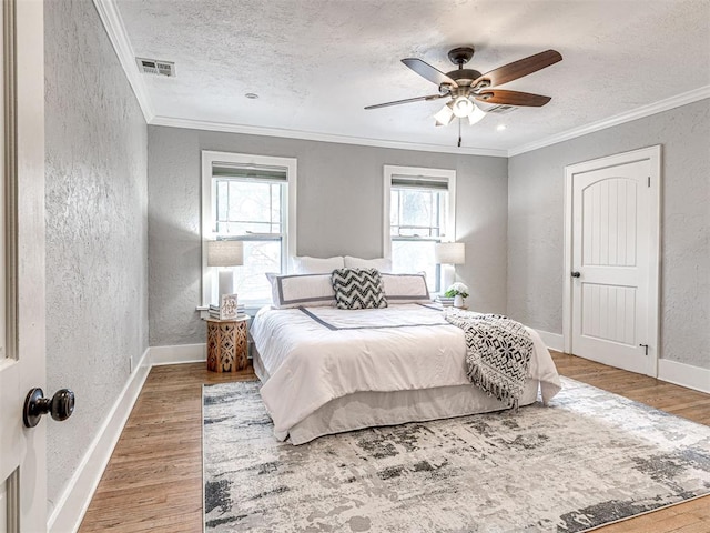 bedroom with hardwood / wood-style flooring, ceiling fan, ornamental molding, and a textured ceiling