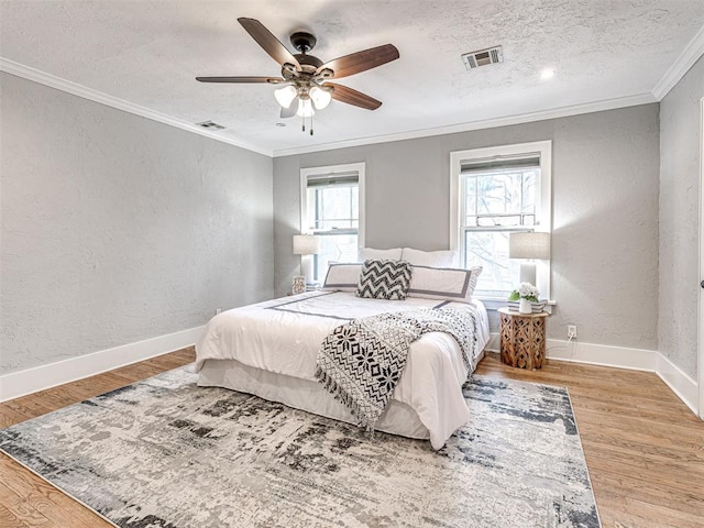 bedroom featuring multiple windows, ceiling fan, a textured ceiling, and light hardwood / wood-style flooring