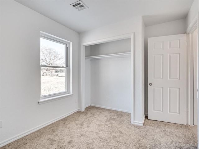 unfurnished bedroom featuring a closet, light colored carpet, and multiple windows