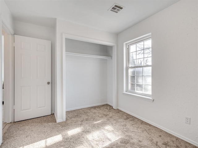 unfurnished bedroom featuring a closet and light carpet