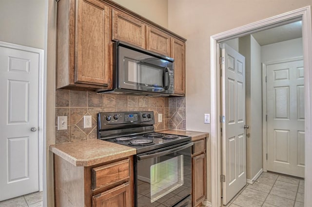 kitchen with tasteful backsplash, light tile patterned floors, and black appliances