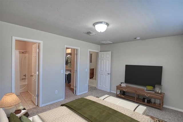 bedroom with light carpet, ensuite bath, a walk in closet, and a closet