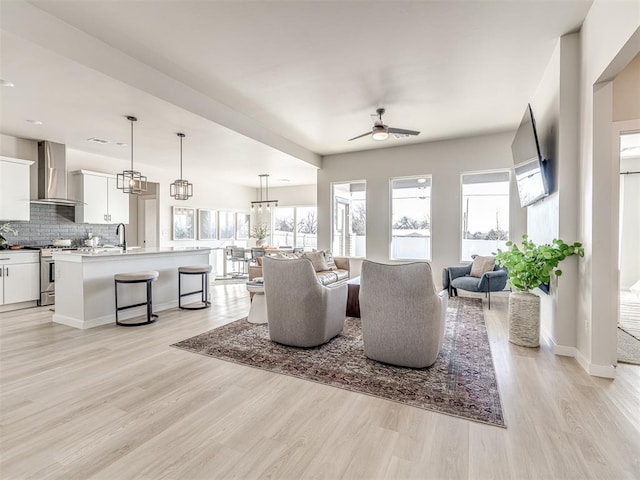 living room featuring ceiling fan, sink, and light hardwood / wood-style flooring