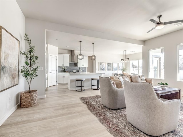 living room with ceiling fan, sink, and light wood-type flooring