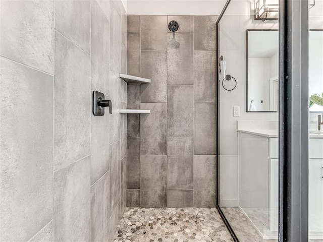 bathroom with tiled shower and vanity