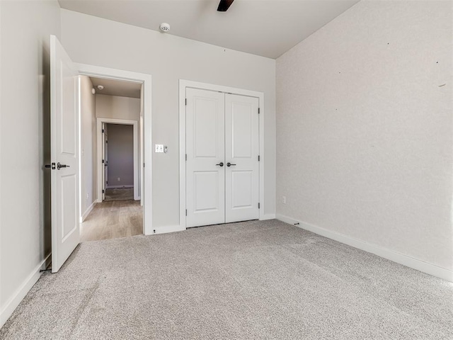 unfurnished bedroom featuring ceiling fan, light colored carpet, and a closet