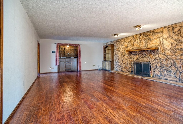 unfurnished living room with hardwood / wood-style flooring, a textured ceiling, and a fireplace