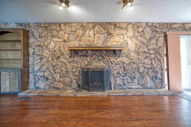 unfurnished living room featuring wood-type flooring, a textured ceiling, and a fireplace