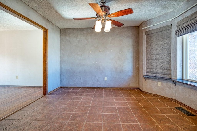 unfurnished room with a textured ceiling, a wealth of natural light, and tile patterned floors