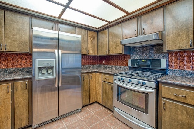 kitchen with light tile patterned floors, stainless steel appliances, and dark stone countertops