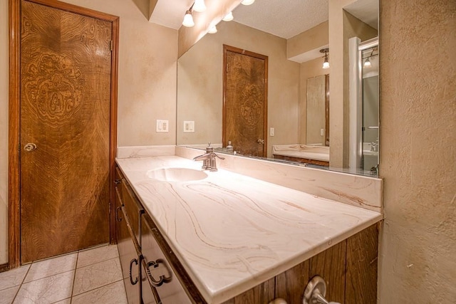 bathroom featuring a textured ceiling, tile patterned floors, and vanity