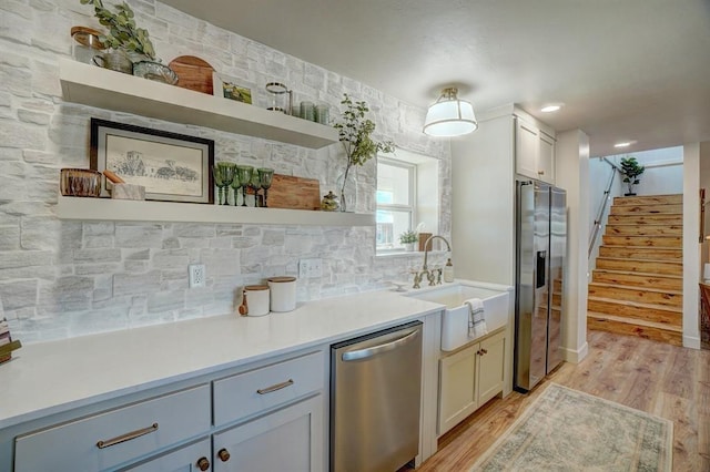 kitchen featuring stainless steel appliances, decorative backsplash, light hardwood / wood-style flooring, and sink