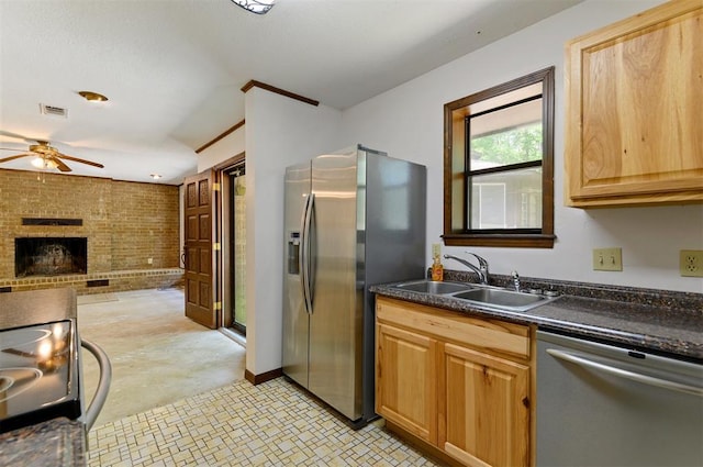 kitchen with stainless steel appliances, sink, a brick fireplace, ceiling fan, and brick wall