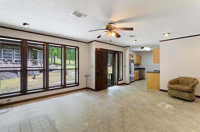 unfurnished living room featuring ceiling fan and a textured ceiling