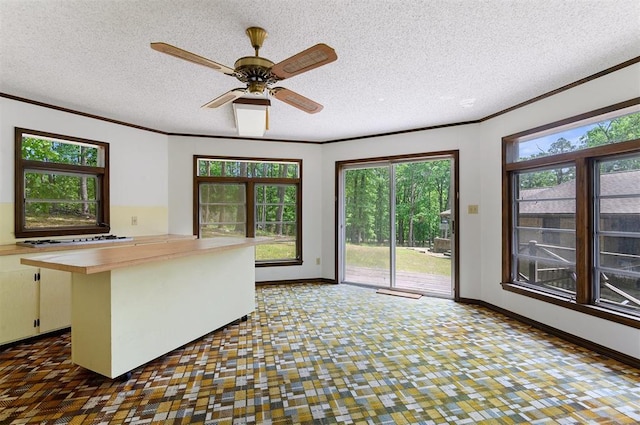 kitchen featuring a center island, a textured ceiling, ornamental molding, white gas stovetop, and white cabinets