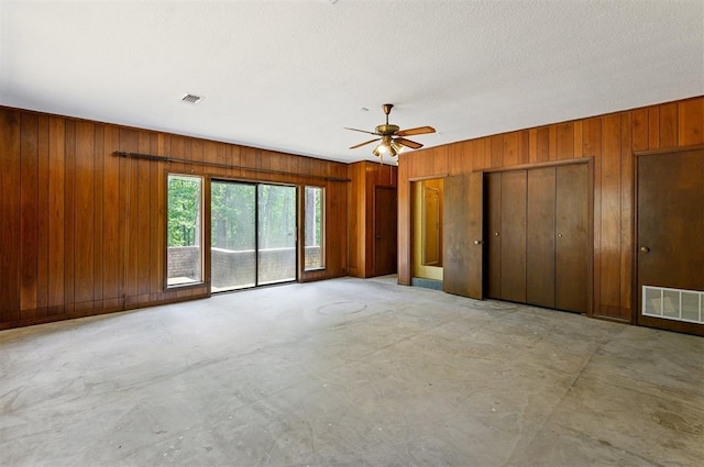 unfurnished bedroom with access to exterior, ceiling fan, and wood walls