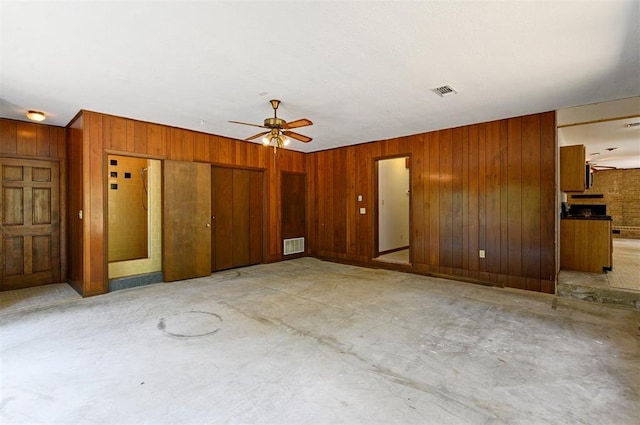 spare room featuring ceiling fan and wood walls