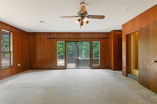 empty room featuring wooden walls and ceiling fan