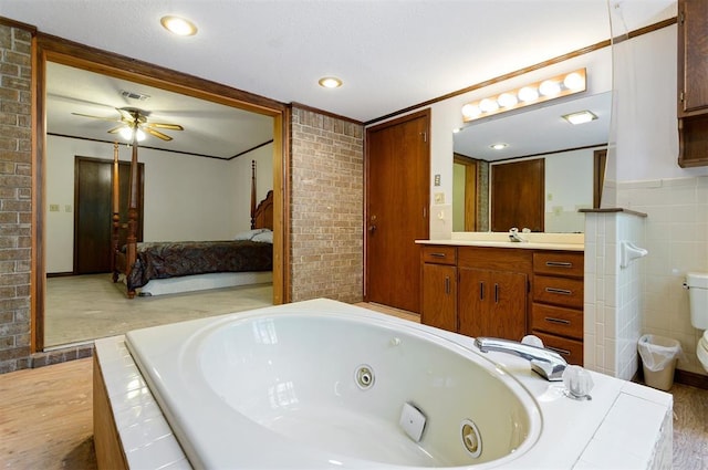 bathroom featuring vanity, ornamental molding, a bath, and toilet