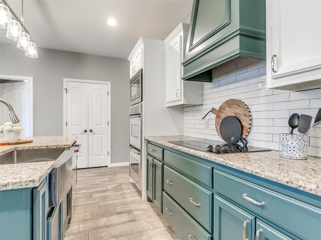 kitchen featuring pendant lighting, stainless steel microwave, custom exhaust hood, white cabinetry, and oven