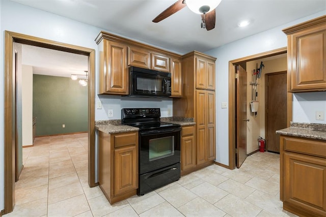 kitchen with black appliances, dark stone countertops, ceiling fan, and light tile patterned floors