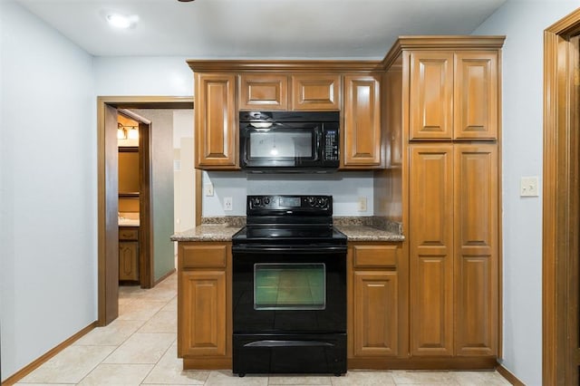 kitchen featuring dark stone countertops, black appliances, and light tile patterned flooring