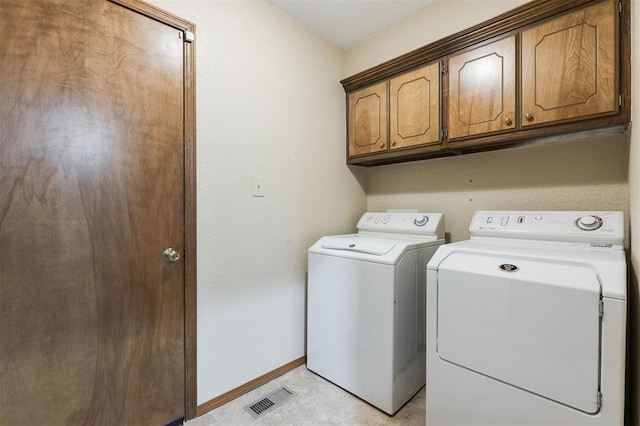 laundry room featuring washer and dryer and cabinets