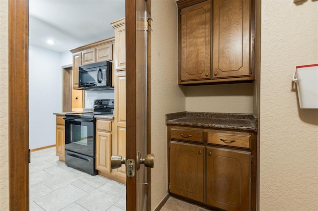 kitchen featuring black appliances, dark stone countertops, and light tile patterned floors