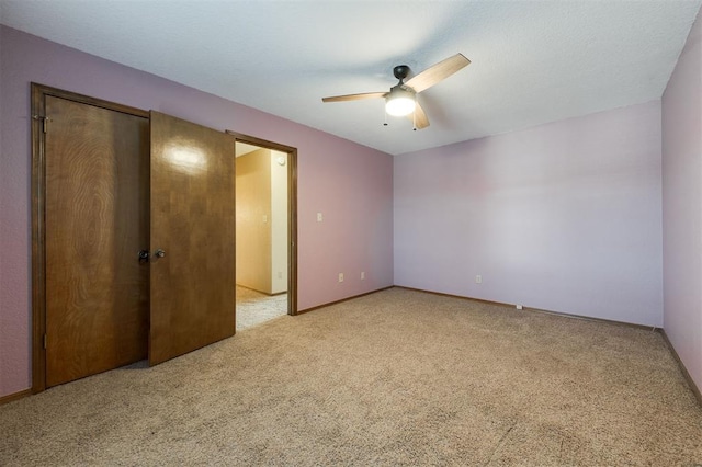 unfurnished bedroom with ceiling fan, a closet, and light carpet