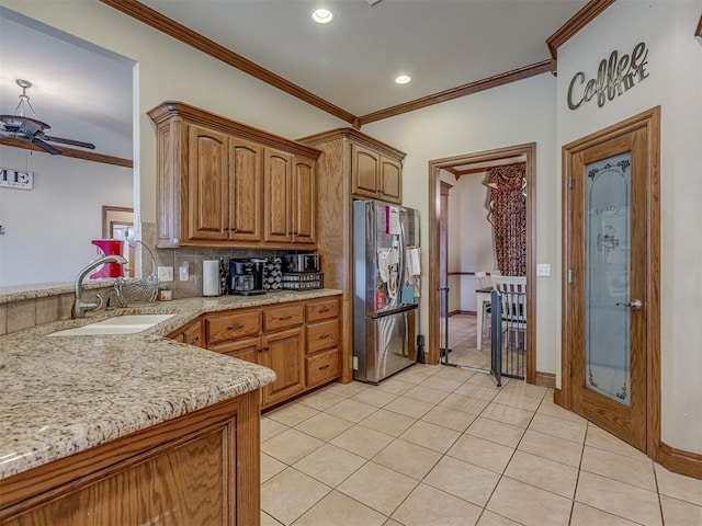 kitchen with sink, crown molding, tasteful backsplash, light tile patterned floors, and stainless steel refrigerator