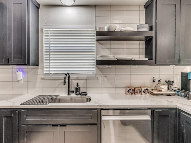 kitchen featuring tasteful backsplash, light stone countertops, sink, and dishwasher