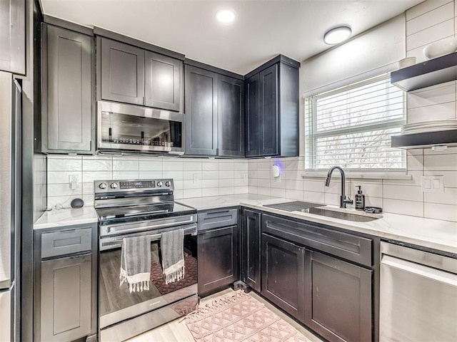 kitchen with stainless steel appliances, tasteful backsplash, sink, and light stone counters