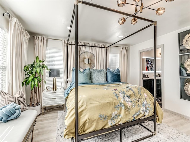 bedroom with ensuite bathroom, multiple windows, and light wood-type flooring