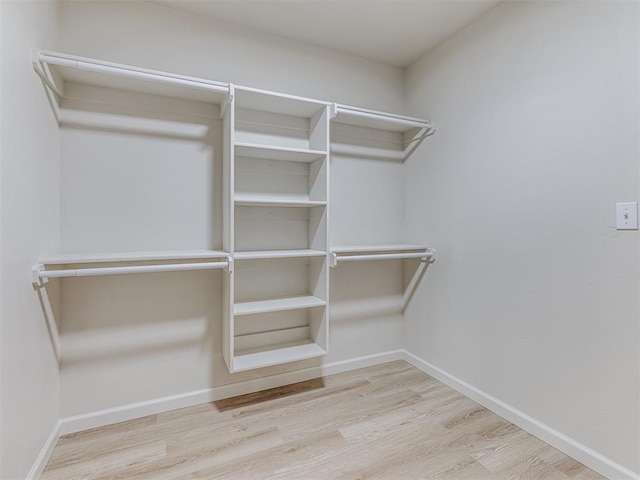 walk in closet with light hardwood / wood-style floors