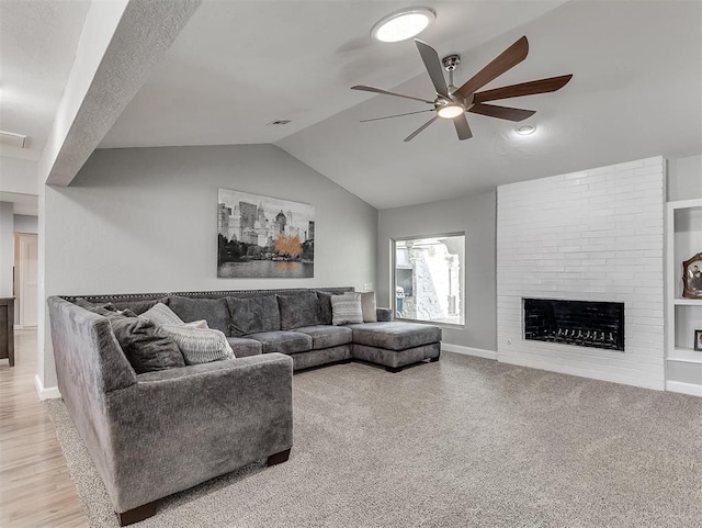 carpeted living room with a large fireplace, ceiling fan, and lofted ceiling