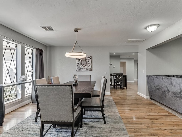 dining room featuring light hardwood / wood-style flooring and a textured ceiling