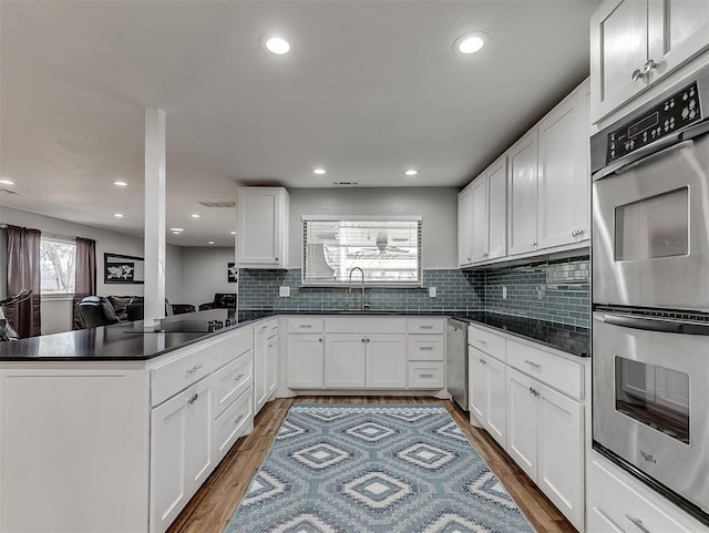 kitchen featuring sink, white cabinetry, kitchen peninsula, and double oven